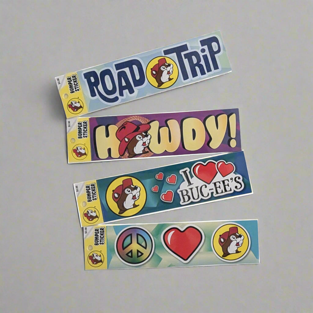 Bumper stickers with different sayings like howdy, road trip, I love Buc-ee's, and Peace love Bucees
